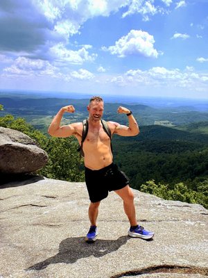 Daisy 200: a hiker flexing on a summit, crisp digital colour